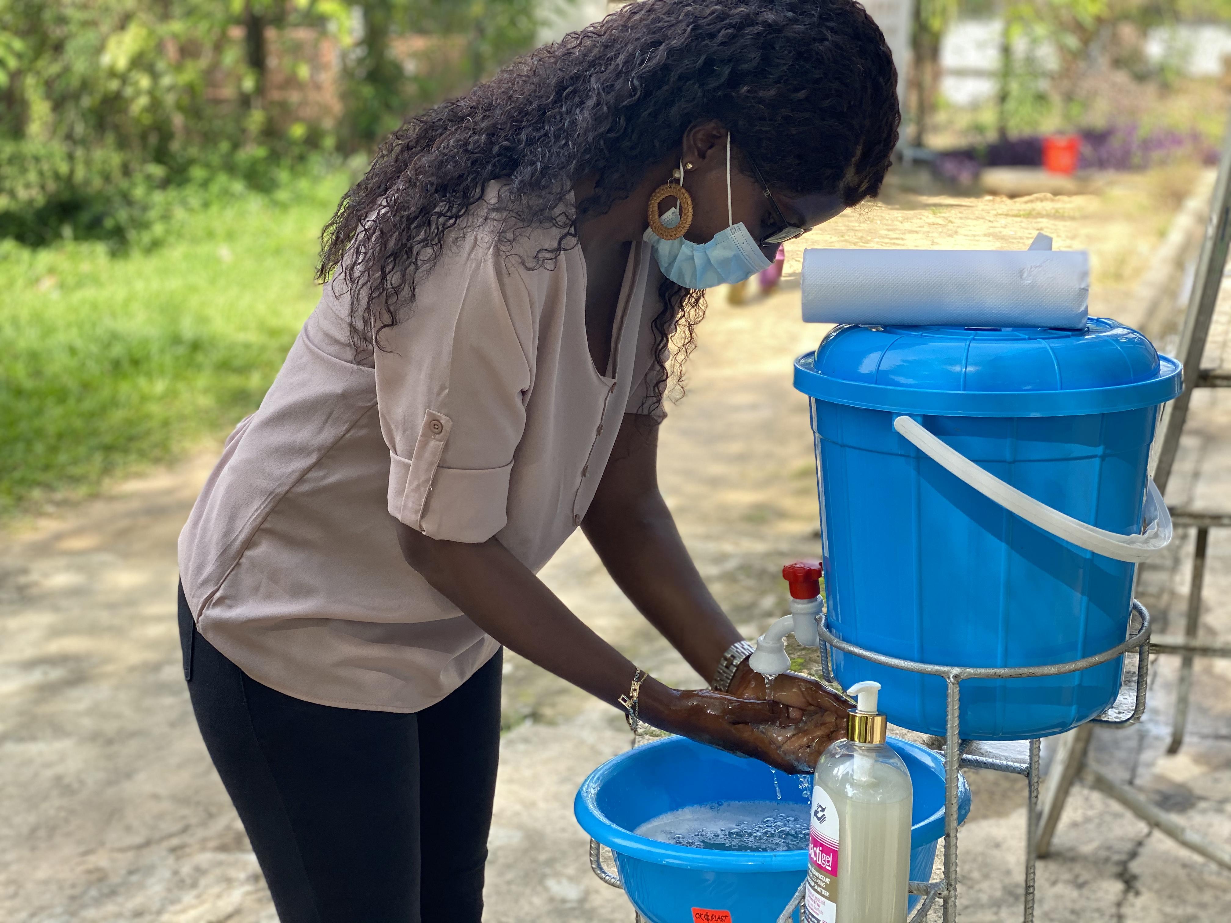 Woman washing hands in a blue bucket